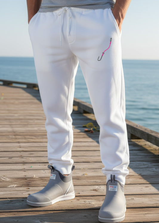 Person wearing white pants with a pink design and gray boots on a wooden dock by the water.