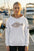 Woman wearing a hoodie with a fish design on a dock with boats in the background