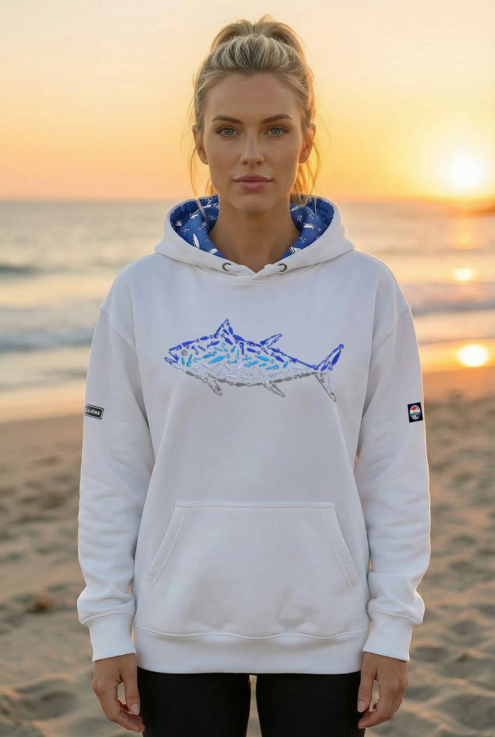 Woman wearing a white hoodie with a shark design on a beach at sunset