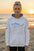 Woman wearing a white hoodie with a shark design on a beach at sunset