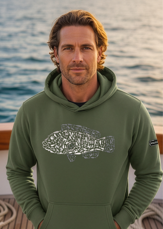 Man wearing a green hoodie with a fish design on a boat deck with ocean in the background