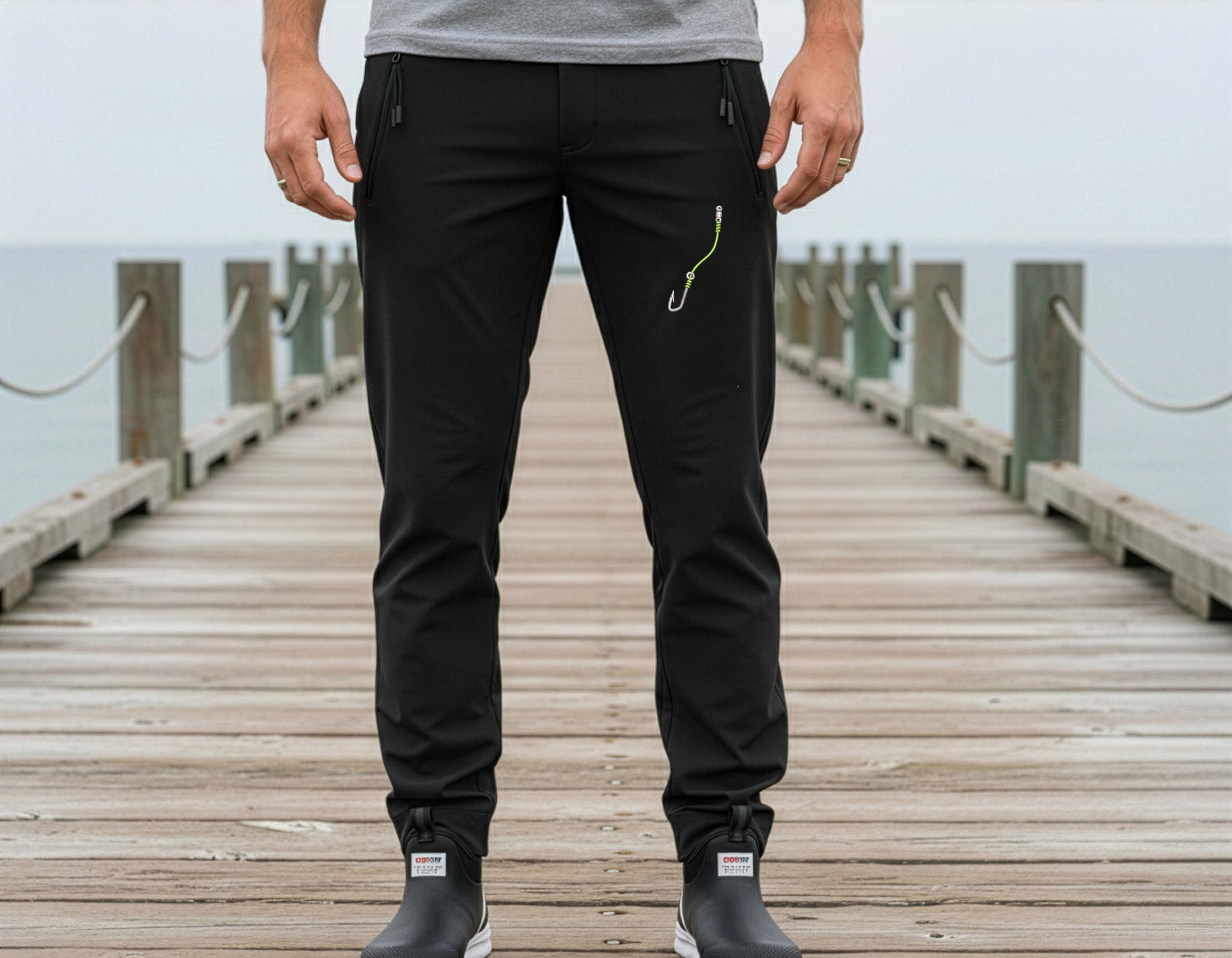 Person wearing black pants on a wooden dock with water in the background