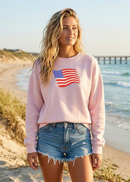 Woman wearing a pink sweatshirt with an American flag on a beach