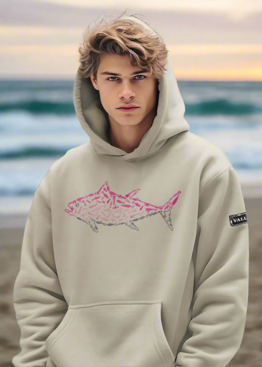 A male model wearing a beige relaxed hoodie with a front pouch pocket and embroidered pink tuna artwork on the front.